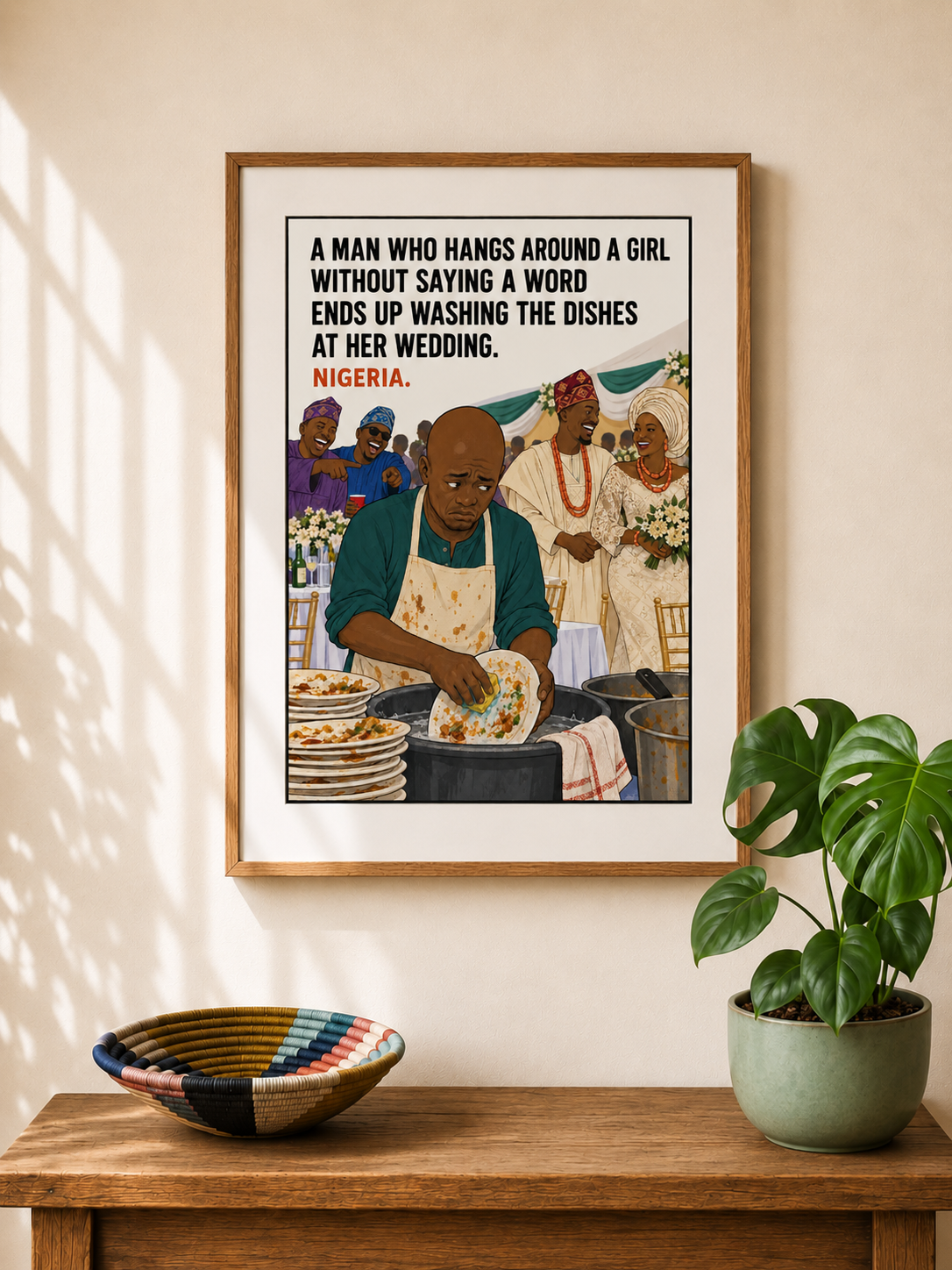 Framed illustrated art print from Nigeria — a dejected man in an apron washes dishes in the background while a bride and groom celebrate at their wedding. Proverb: A man who hangs around a girl without saying a word ends up washing the dishes at her wedding. From Mopti's African Proverbs Series.