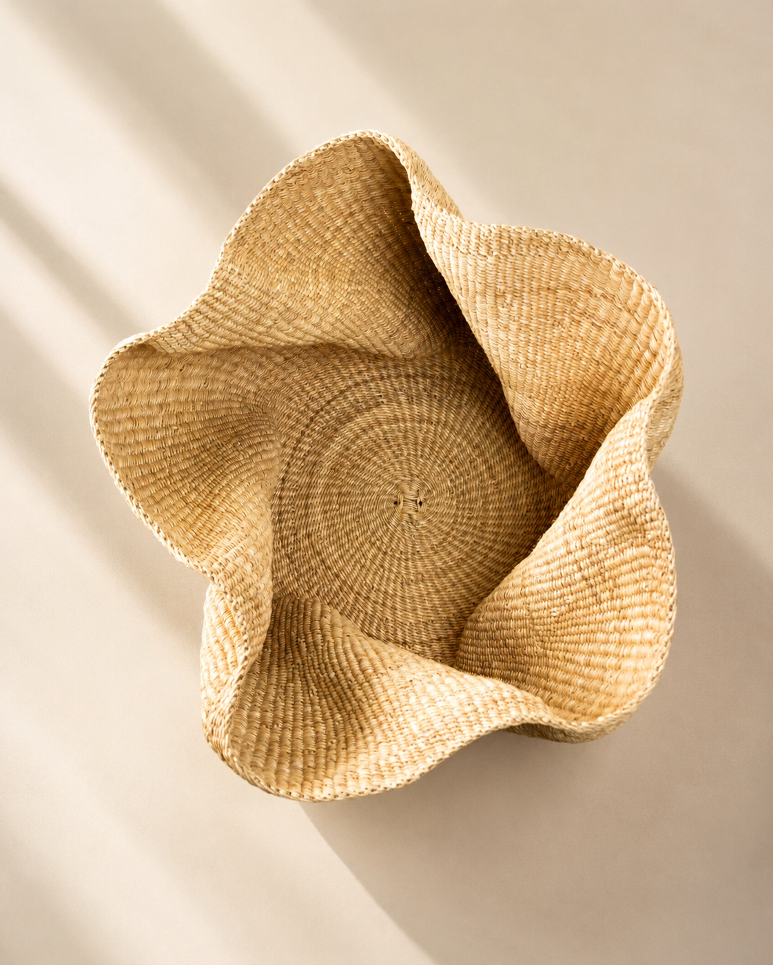 Handwoven elephant grass basket in natural straw with a wavy petal-shaped rim, seen from above — Pakurigo Wave Basket PW05 by Mopti Living
