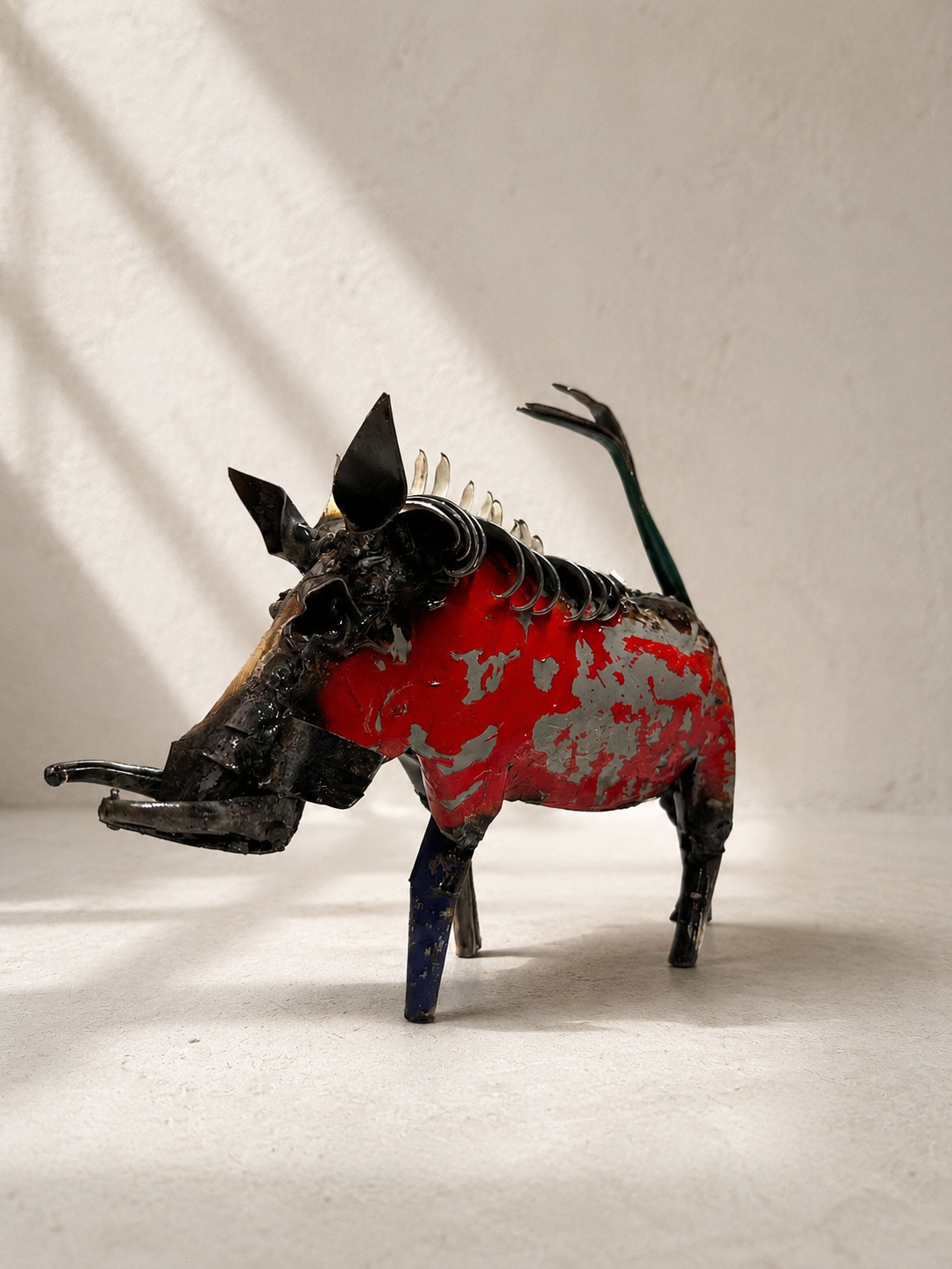 Handmade recycled metal warthog sculpture with colourful layered panels in red, blue, yellow and green — Mopti Living