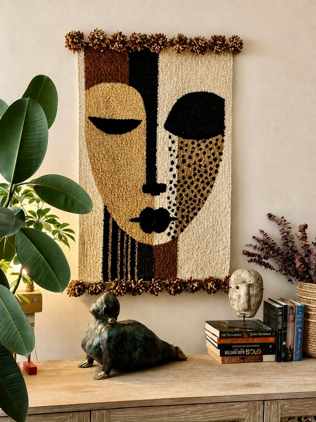 Handmade wool wall hanging with a split-face graphic motif in cream, black and gold, with pompom edging – Mopti Living