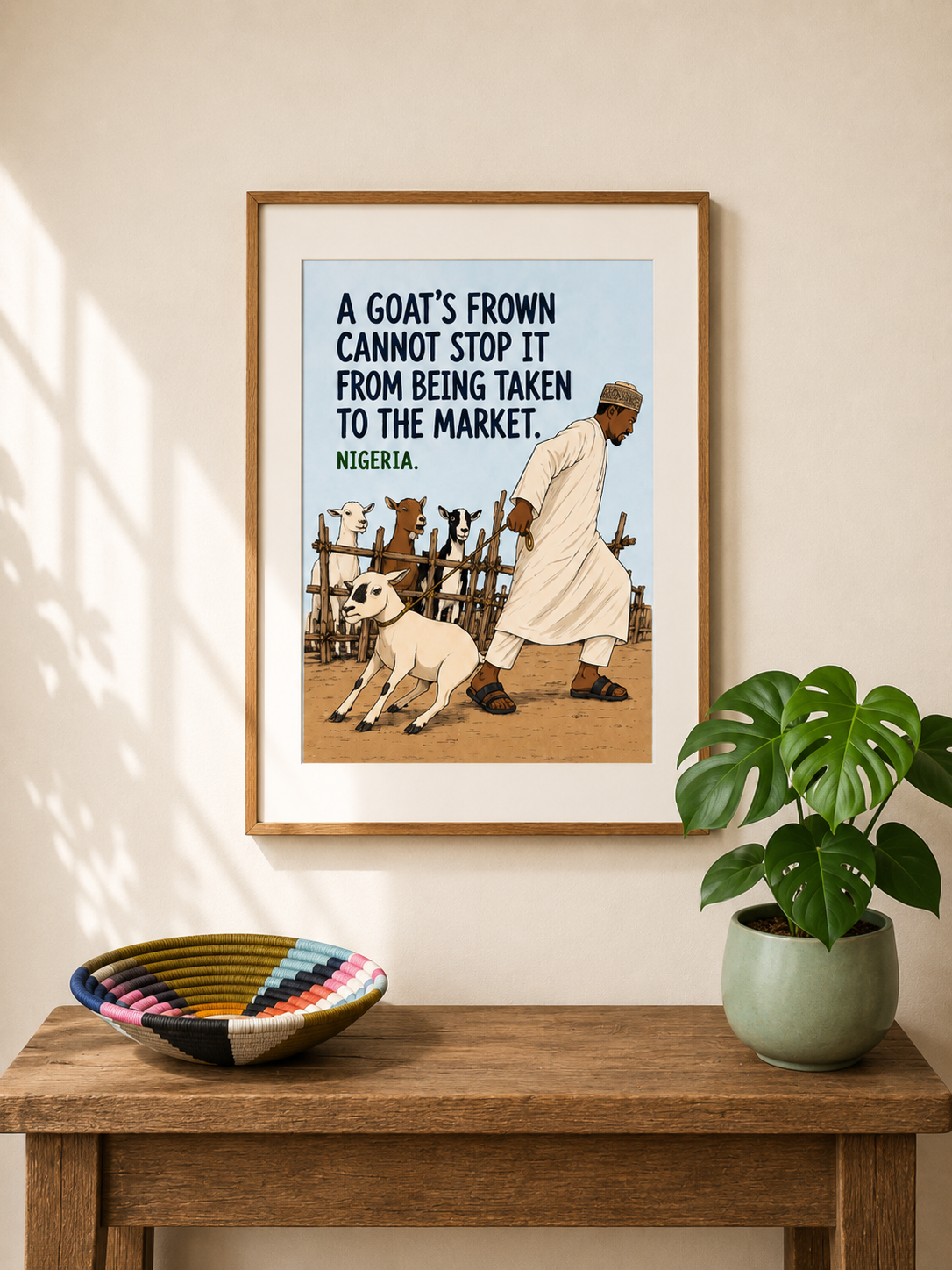 Framed illustrated art print from Nigeria — a man in a white kaftan drags a reluctant goat away from a pen of watching goats. Proverb: A goat's frown cannot stop it from being taken to the market. From Mopti's African Proverbs Series.