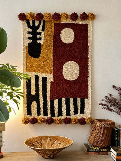 Handmade wool wall hanging with geometric colour-block design in rust, ochre and black, with pompom edging – Mopti Living