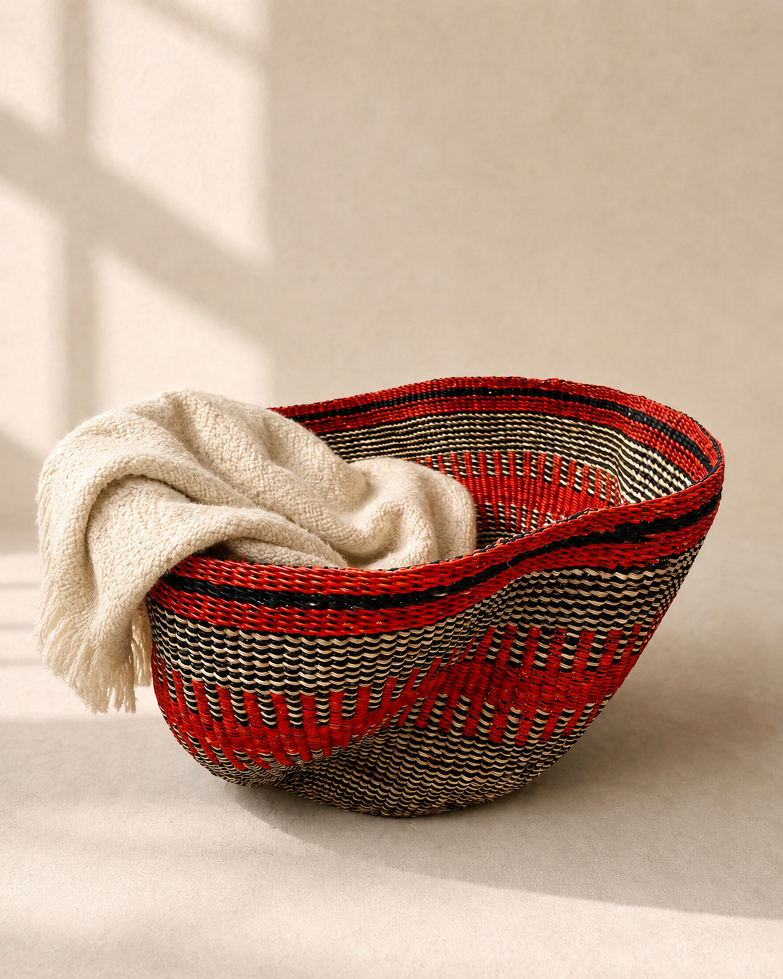Handwoven elephant grass basket in orange and black with a deep bowl shape and curved rim — Pakurigo Wave Basket PW04 by Mopti Living

