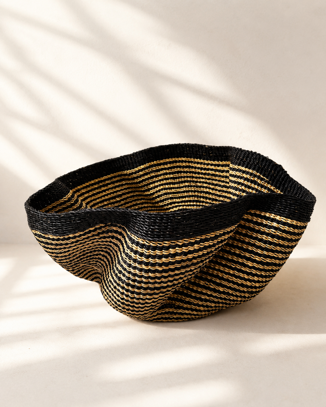 Handwoven elephant grass basket with wavy scalloped rim in black and natural gold stripes — Pakurigo Wave Basket PW03 by Mopti Living