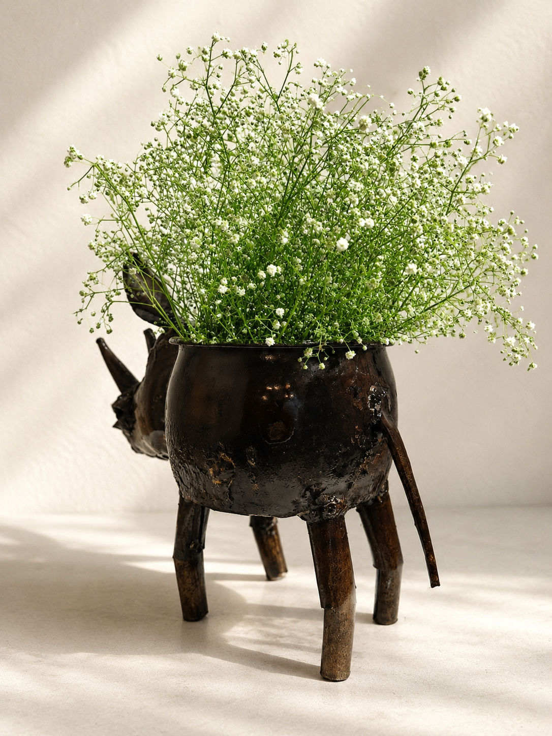 Handmade recycled metal rhino planter with dark finish and visible joins — Mopti Living