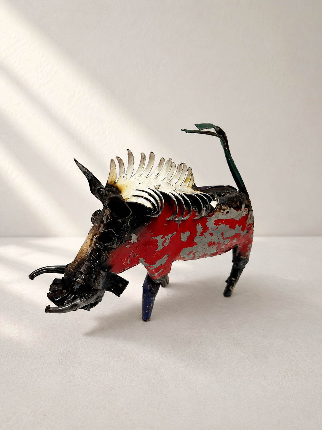 Handmade recycled metal warthog sculpture with colourful layered panels in red, blue, yellow and green — Mopti Living