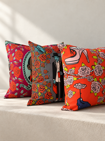 Three Shine Shine cushions with colourful portrait, rose and fashion prints arranged on a cream sofa.
