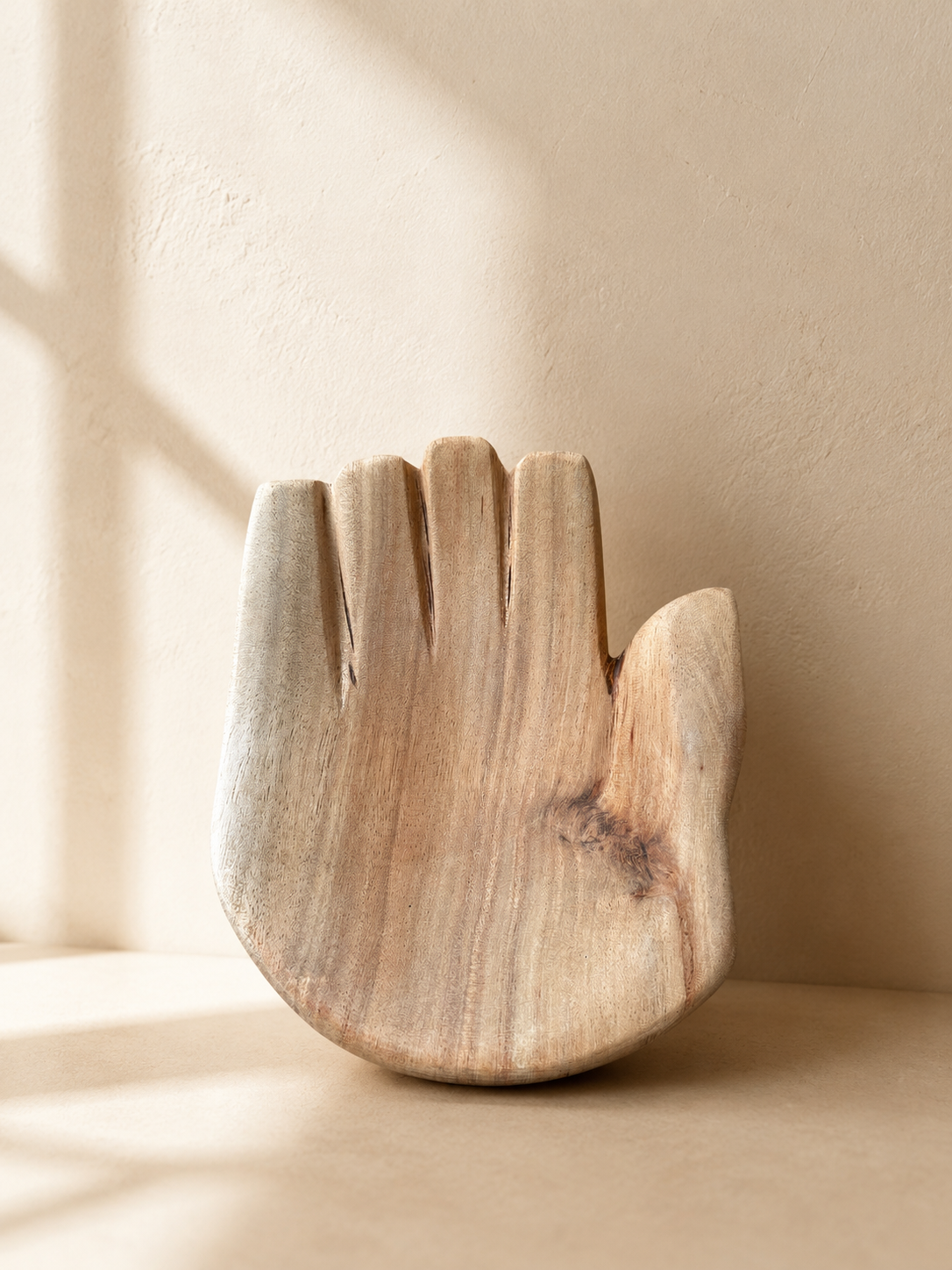 Hand-carved wooden closed hand sculpture with palm facing upward, showing natural wood grain and tool marks — Mopti Living