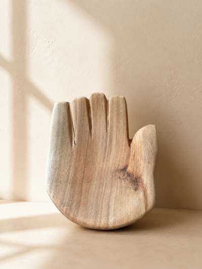 Hand-carved wooden closed hand sculpture with palm facing upward, showing natural wood grain and tool marks — Mopti Living